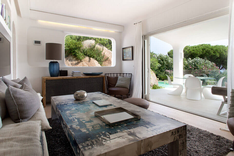 Modernes Wohnzimmer mit minimalistischem Design, neutralen Tönen, einem großen Fenster mit Blick auf die Felslandschaft, eleganten Möbeln von erfahrenem Baumanagement und künstlerischer Dekoration, darunter einem großen abstrakten Couchtisch.
